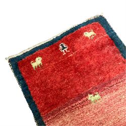 Small Persian Gabbeh crimson ground thick pile rug, decorated with stylised camel and figure motifs, encased with a plain indigo border, retailed by Fired Earth