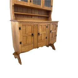 'Gnomeman' adzed oak dresser, three lead glazed doors enclosing two height fixed plate racks and one exposed plate rack, over three cupboard doors enclosing one loose shelf and three drawers, raised on panel end supports, carved with gnome signature, by Thomas Whittaker of Littlebeck