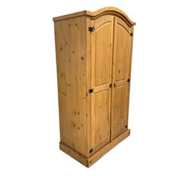 Traditional pine wardrobe, the arched top over two panelled doors enclosing interior fitted for hanging and with shelf, raised on a skirted base W102cm, H190cm, D57cm