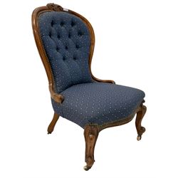 Victorian mahogany framed nursing chair, foliate cartouche carved cresting rail on spoon back, upholstered in contemporary buttoned blue patterned fabric, raised on scrolled cabriole front supports with ceramic castors