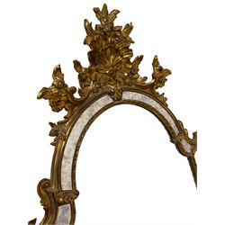 Gilt cushion framed wall mirror, the shell and flower head pediment with extending floral decoration, scrolled foliate detail to uprights, plain mirror plates with moulded inner slip