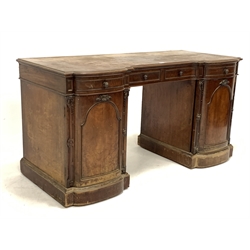 Victorian mahogany twin pedestal desk, inverted break front over one long and two short drawers, arched panelled doors to base enclosing one bank of three drawers and one bank of three slides, with carved applied floral decoration, raised on plinth and castors, W148cm, H77cm, D65cm
