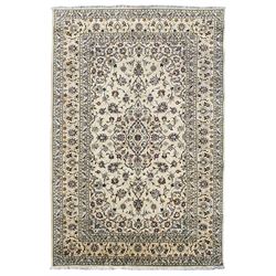 Persian Kashan ivory ground rug, the central floral pole medallion within a sparsely decorated field of scrolling foliate tendrils with palmette motifs, the guarded border with repeating stylised plant motifs within scrolling branches and flower heads
