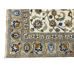 Persian Kashan ivory ground rug, the field with a central floral medallion surrounded by scrolling tendrils of branches with palmette motifs, the multi-band border with repeating stylised floral patterns and acanthus leaves
