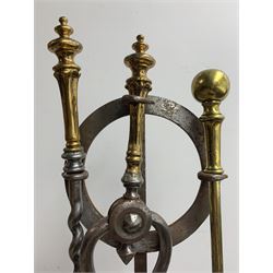 Steel fireside companion stand of wrythen form hung with a pair of matching brass mounted implements, a brass poker and a pair of coal scissors H103cm