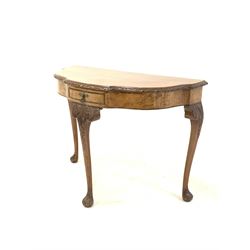 20th century Queen Anne style burr walnut serpentine bow front console table, the cross banded top with floral moulded edge over single frieze drawer, raised on leaf carved cabriole supports W101cm