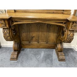 Pair Gothic style oak console table with mirror, pointed ogee arch decorated with trailing scrolled foliage, the tracery uprights with crocketed pinnacles, moulded reverse break-front top supported by two scrolling supports carved with foliage and berries, pieced with quatrefoils, panelled back with cusped pediments