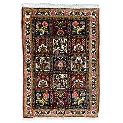 Persian Bakhtiari crimson ground rug, the field with three rows of panels depicting varying floral designs, banded ivory border with repeating flower heads and leafage