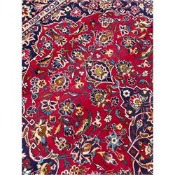 Persian red ground Kashan rug, the field with indigo central medallion surrounded by trailing and interlaced branches with stylised flower head motifs, guarded border with repeating floral design