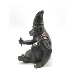 Japanese Meiji  patinated bronze figure of a macaque monkey modelled as a Sarumawashi, seated cross legged wearing a cape and pointed cap with outstretched arm H18cm, signature mark to base 