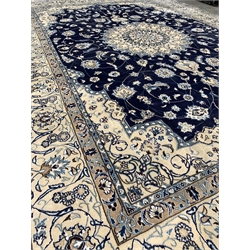 Persian ivory ground carpet, central medallion on blue field decorated with interlaced foliate