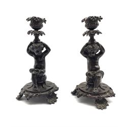 Pair of patinated bronze figural candlesticks, each in the form as a seated Cherub, supporting a fruit cast nozzle, H21.5cm 