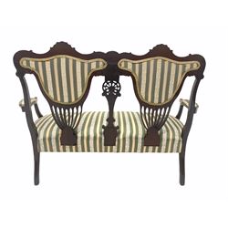 Late Victorian mahogany two seat salon settee, floral and pierce carved back rest, upholstered in stripped fabric, raised on cabriole front supports W127cm