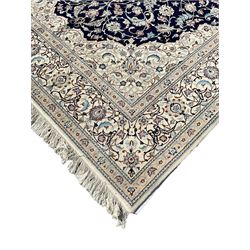 Persian Nain Shishla wool and silk inlaid carpet, blue ground with central rosette medallion, the field decorated with interlacing branch and stylised plant motifs, scrolling design borders and spandrels, with signature panel to one end 
