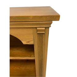 Waxed pine open bookcase, rectangular top over shaped frieze, fitted with two shelved flanked by reeded uprights, on plinth base
