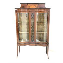 Edwardian mahogany serpentine display cabinet, the raised back inlaid with boxwood stringing, cornucopias issuing flowers centred by fan, over frieze with further inlay, two doors enclosing two shelves, raised on slender square tapered and splayed support W107cm, H178cm, D40cm