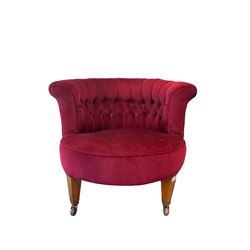 Late Victorian tub-shaped salon chair, buttoned back upholstered in red, square tapering supports with brass and ceramic castors