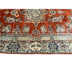 Persian Kerman red ground rug, the field with a central medallion surrounded by spaced floral garlands and bouquets, the secondary pale blue blue border with scrolling foliate vines and flower heads, the outer busy band with repeating plant motifs