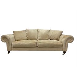 DFS - three seater sofa, upholstered in cream fabric, raised on turned and reeded supports, terminating in brass castors 