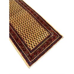 Persian Aarak golden wheat ground runner, the field decorated with repeating Boteh motifs, the main border band with trailing design interspersed with stylised geometric motifs, within guard bands