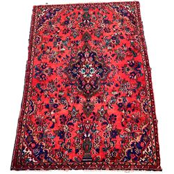 Iranian red ground rug, deep blue, red, ivory and green medallion on field decorated with urns and stylised foliate 259cm x 164cm