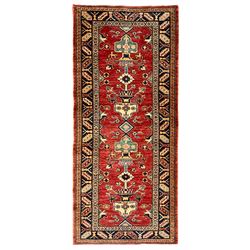 Persian design red ground rug, the field decorated with a central pole medallion comprising of urns and floral patterns, the indigo border with geometric repeating designs
