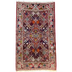 Afghan crimson ground rug, the central lozenge and matching spandrels decorated with candelabra motifs, the indigo field with all-over lozenge decoration of contrasting panels, the guarded border with repeating stylised flower heads and garlands