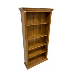 Oak bookcase, the projecting dentil cornice over four adjustable shelves with reeded sides, raised on a plinth base 