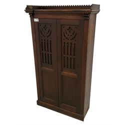 Victorian oak freestanding cupboard, lappet carved cornice over two blind-fretwork doors of gothic design, enclosing three shelves, skirted base