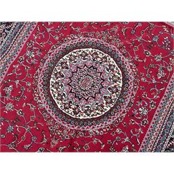 Persian design crimson ground rug, the field decorated with circular medallion surrounded by trailing branches and foliate motifs, the spandrels and border decorated with stylised plant motifs 