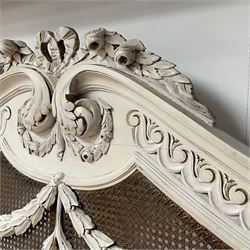 Mid-to-late 20th century French bergère 5' Kingsize bedstead, the shaped pediment carved with tied ribbon with extending foliage decorated and Vitruvian scroll frieze, mounted by bellflower festoons and turned finials, curved footboard with further festoons and trailing flowerheads, on turned feet with brass castors