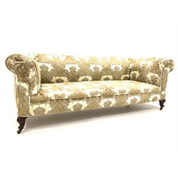 Late Victorian drop arm chesterfield sofa upholstered in textured floral fabric, raised on walnut leaf carved cabriole front supports and castors
