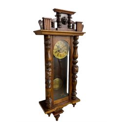A late 19th century German spring driven wall clock in a mahogany case with a fully glazed door, case with applied carvings and finials, two-part dial with a gilt centre and Ivorine chapter, with Roman numerals, minute track and gothic steel hands, 8-day movement striking the hours and half hours on a coiled gong, with gridiron pendulum and brass faced bob.

