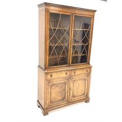 Georgian style mahogany bookcase cabinet, dentil cornice over astragal glazed doors enclosing three adjustable shelves, two drawers under with lion mask pull handles, two panelled cupboards to base enclosing a further shelf, raised on shaped bracket supports, W115cm, H207cm, D41cm