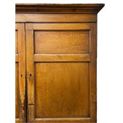 George III scumbled pine housekeeper's cupboard on chest, projecting moulded cornice over two panelled doors enclosing two shelves, the lower section fitted with three long drawers with turned handles, shaped apron on tapering bracket feet, scumbled paint finish to resemble oak 