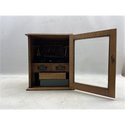 Early 20th century oak smokers cabinet with glazed hinged door enclosing two drawers and removable pipe rack in the form of a gate, with various pipes and smoking paraphernalia, H34cm, D19cm, W29cm