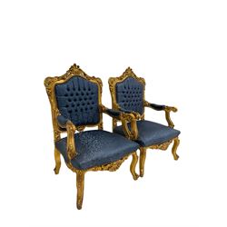 Pair French style gilt wood armchairs, the cresting rail decorated with shell and flower head motifs, upholstered in buttoned blue fabric with scrolling foliate pattern, floral carved cabriole supports