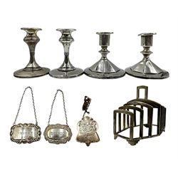 Pair of silver candlesticks of panel sided design on a circular foot H10cm Birmingham 1939, another pair H11cm Birmingham 1914, silver six division toast rack and three decanter labels  