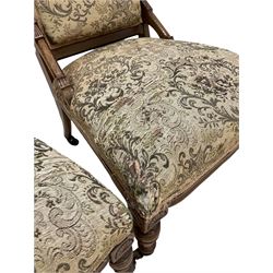 Pair of Victorian bedroom chairs, the carved cresting rail over back and seat upholstered in floral fabric, raised on turned supports, terminating in ceramic castors 