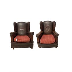 Pair of 20th century leather wingback armchairs, with drop in seat pad, raised on castors 