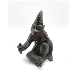 Japanese Meiji  patinated bronze figure of a macaque monkey modelled as a Sarumawashi, seated cross legged wearing a cape and pointed cap with outstretched arm H18cm, signature mark to base 