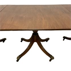 Regency design mahogany triple pillar dining table, oval top with reeded edge, over three turned vasiform pedestals with reeded sabre supports, terminating to brass hairy paw feet and castors