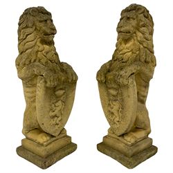 Pair of composite stone garden ornaments in the form of lions holding heraldic shields