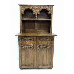  20th century carved oak dresser with one height plate rack over panelled cupboard enclosing shelf and two drawers, raised on compressed bun supports, W100cm, H168cm, D52cm  