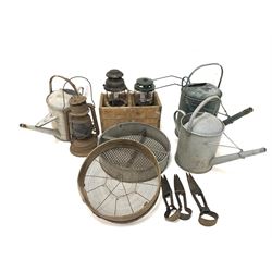 Three vintage galvanised metal watering cans, together with three garden shears, two sieves and three oil lamps 