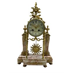 A late 19th century French portico clock on a break front variegated marble base with two conforming marble pillars, with a gilt drum case and eight-day countwheel striking movement striking the hours and half hours on a bell, enamel dial with Arabic numerals and a floral swag, Louis XV pierced gilt hands enclosed within a convex glass and brass bezel, with a visible sunburst pendulum.



