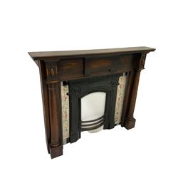 Oak fireplace with two carved columns and Greek keys, surrounding iron fire insert with separate floral tiles  