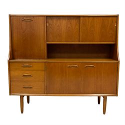 Jentique - mid-20th century teak highboard or wall unit, the top section fitted with drinks cupboard enclosed by fall-front door, two sliding doors concealing shelf, lower section fitted with three graduating drawers and two cupboard doors, raised on tapering supports