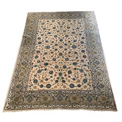Kashan beige ground carpet, the central field decorated with scrolled floral motifs, enclosed by triple guarded border 417cm x 301cm