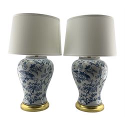 Pair of Chinese blue and white porcelain table lamps, each of inverted baluster form, decorated Exotic birds perched in flowering trees raised upon gilt circular base, H64cm including shade 